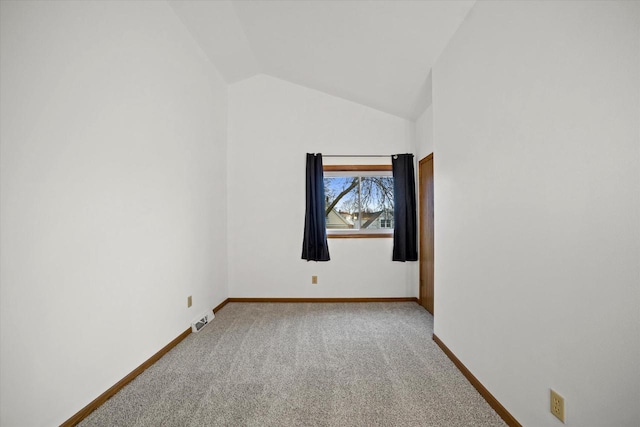 spare room featuring carpet and vaulted ceiling