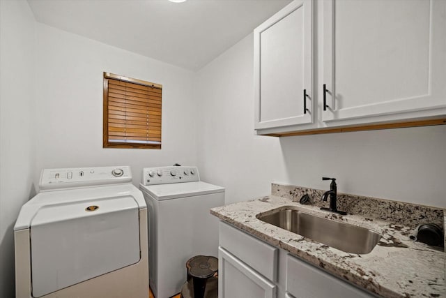 clothes washing area featuring washing machine and clothes dryer, sink, and cabinets