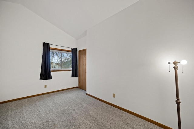 carpeted empty room featuring lofted ceiling