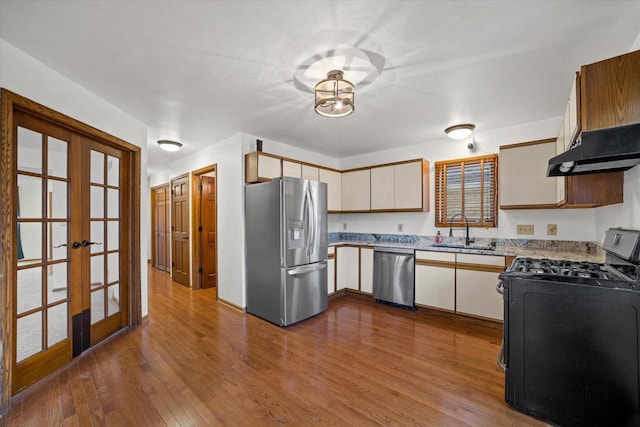 kitchen with french doors, sink, stainless steel appliances, light hardwood / wood-style floors, and exhaust hood