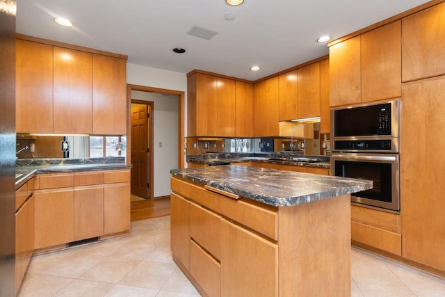 kitchen with stainless steel appliances, a kitchen island, and light tile patterned flooring