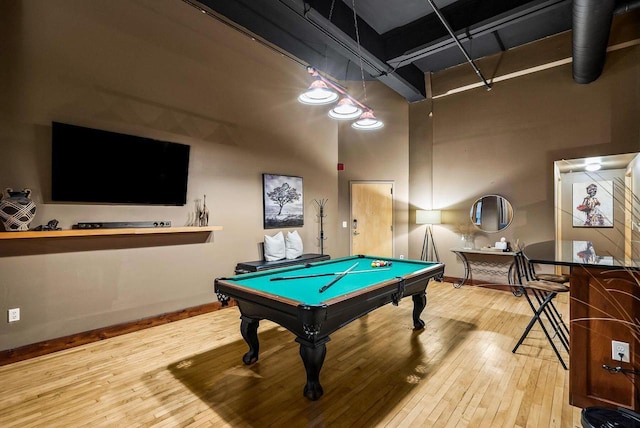 rec room featuring billiards, a towering ceiling, and hardwood / wood-style flooring