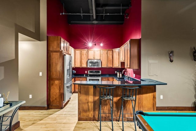 kitchen featuring light hardwood / wood-style floors, billiards, a high ceiling, and appliances with stainless steel finishes