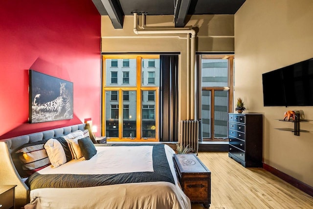 bedroom featuring beamed ceiling and light wood-type flooring