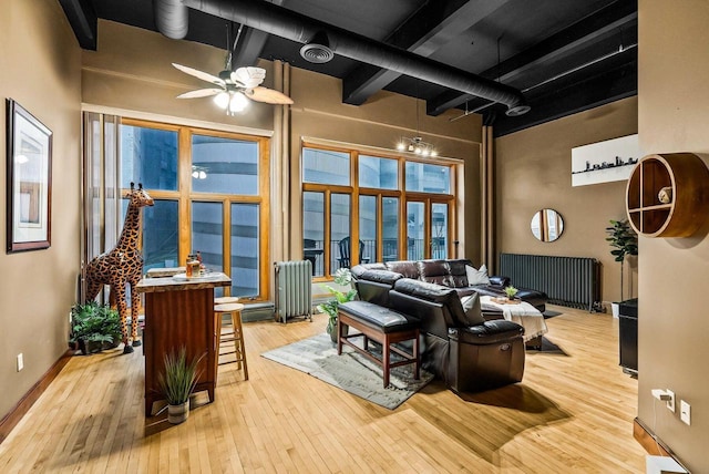 living room featuring radiator heating unit, light wood-type flooring, and a high ceiling