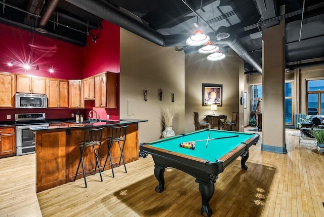 game room featuring sink, a towering ceiling, light hardwood / wood-style floors, and pool table