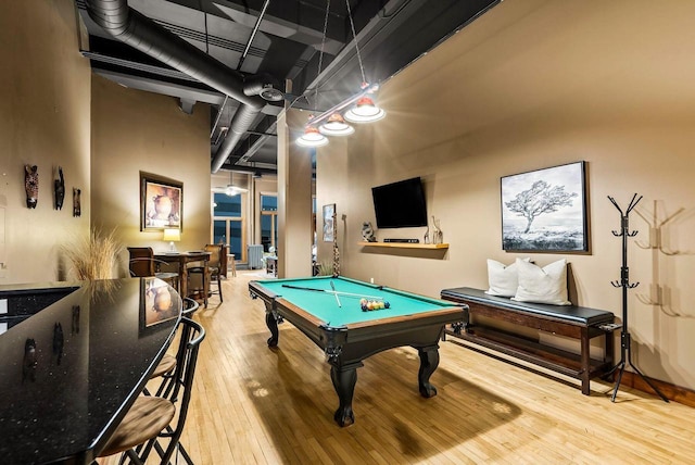 recreation room featuring hardwood / wood-style flooring, a towering ceiling, and pool table