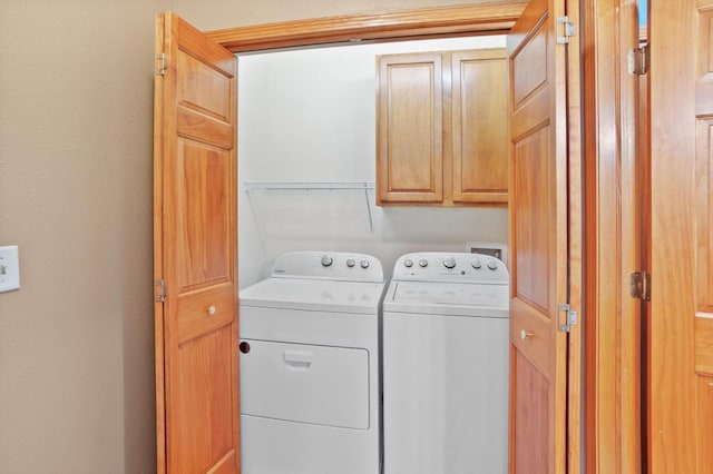 clothes washing area featuring separate washer and dryer and cabinets