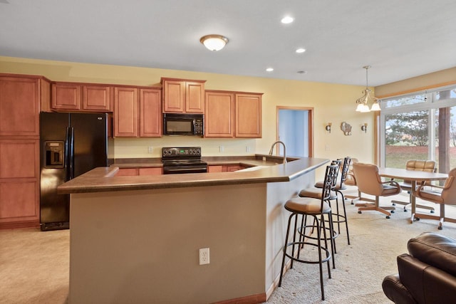 kitchen with light carpet, black appliances, sink, hanging light fixtures, and a kitchen bar