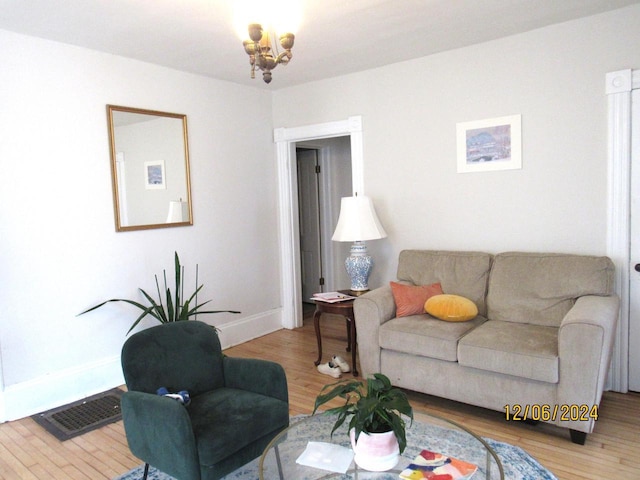 living room featuring light wood-type flooring and a notable chandelier