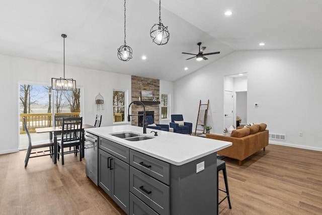 kitchen with sink, light wood-type flooring, a kitchen island with sink, and vaulted ceiling