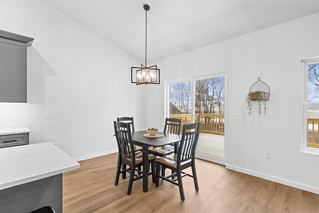 dining space featuring light wood-type flooring, an inviting chandelier, and lofted ceiling