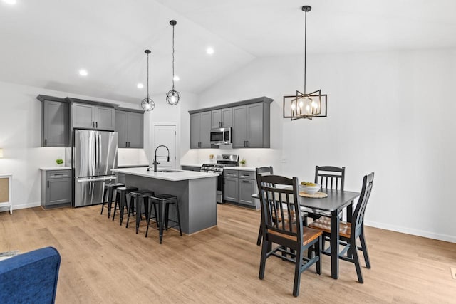 kitchen featuring decorative light fixtures, stainless steel appliances, gray cabinetry, and light hardwood / wood-style floors