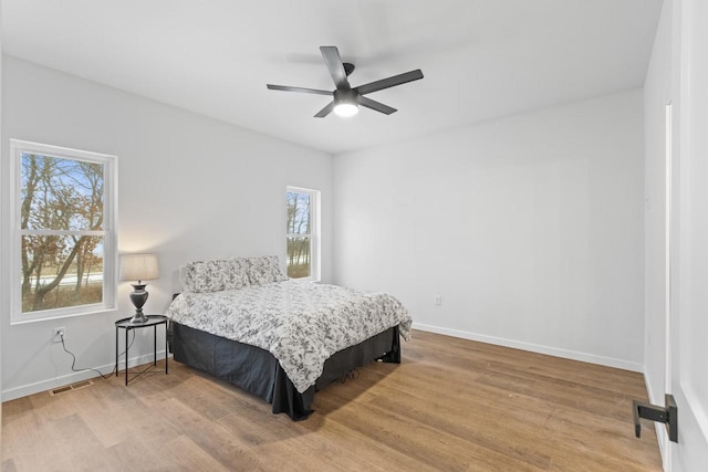 bedroom featuring wood-type flooring, multiple windows, and ceiling fan