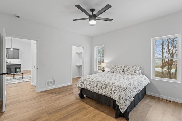 bedroom featuring ceiling fan, wood-type flooring, and multiple windows