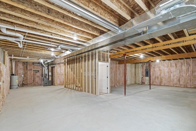 basement featuring heating unit, water heater, and electric panel