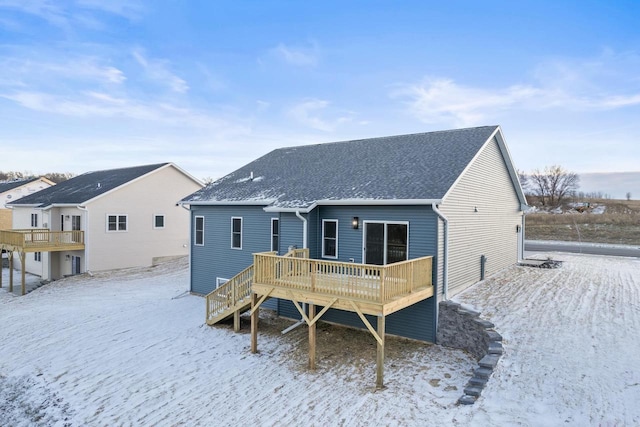 snow covered back of property featuring a deck