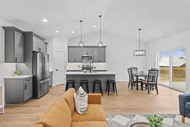 living room with a chandelier, light hardwood / wood-style flooring, lofted ceiling, and sink