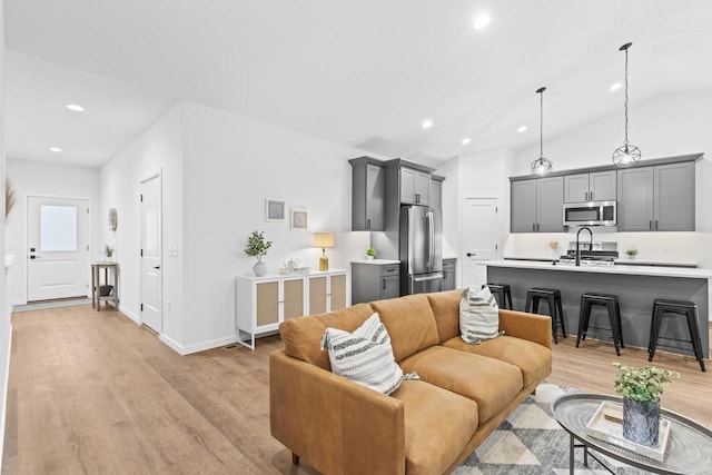 living room with light hardwood / wood-style floors, lofted ceiling, and sink