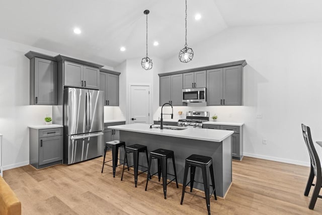 kitchen featuring stainless steel appliances, vaulted ceiling, sink, pendant lighting, and gray cabinets