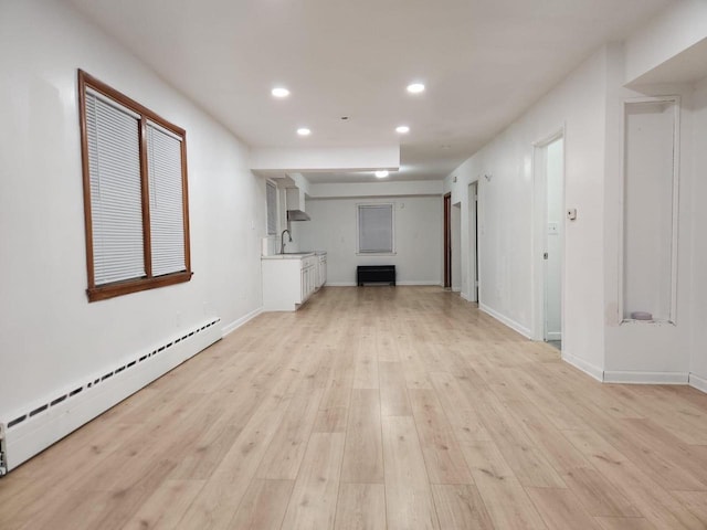 unfurnished living room with a baseboard radiator, light hardwood / wood-style flooring, and sink