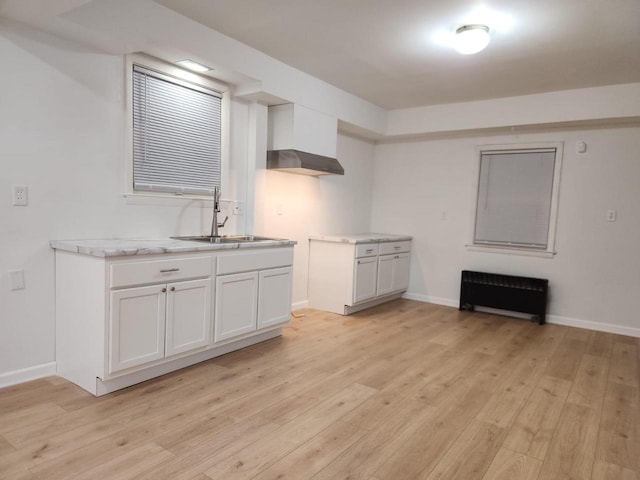 kitchen with radiator, sink, white cabinets, and light wood-type flooring