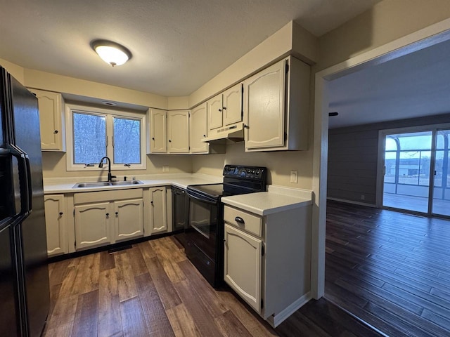 kitchen featuring dark wood-type flooring, sink, white cabinets, and black appliances