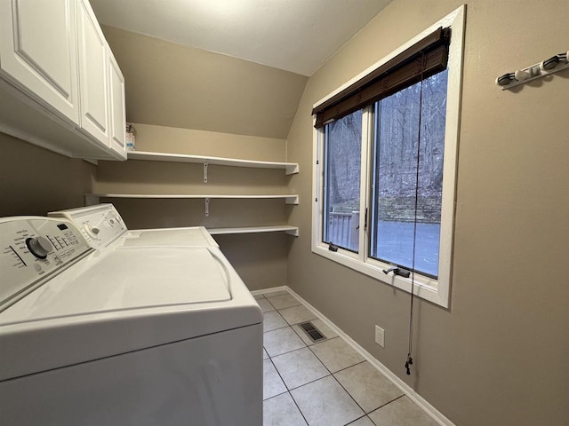 clothes washing area with cabinets, light tile patterned flooring, and washer and dryer