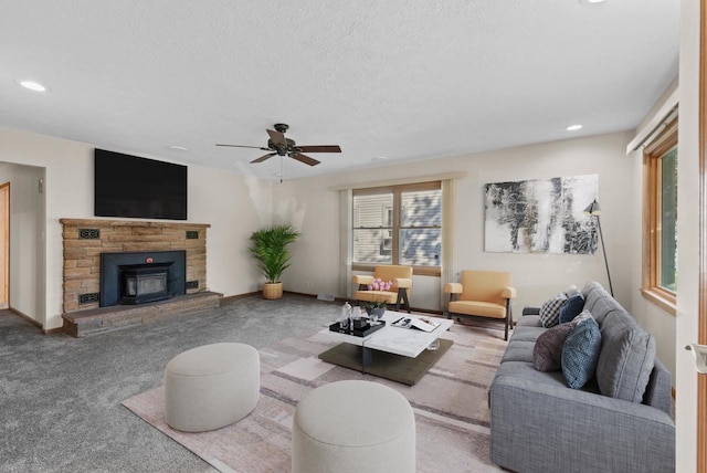 carpeted living room with ceiling fan, a wood stove, and a textured ceiling