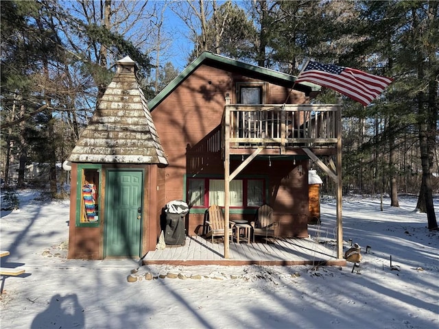 snow covered back of property with a balcony