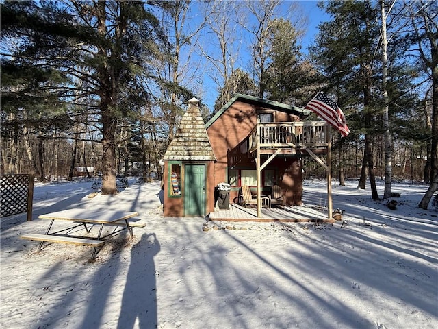 snow covered back of property with a deck