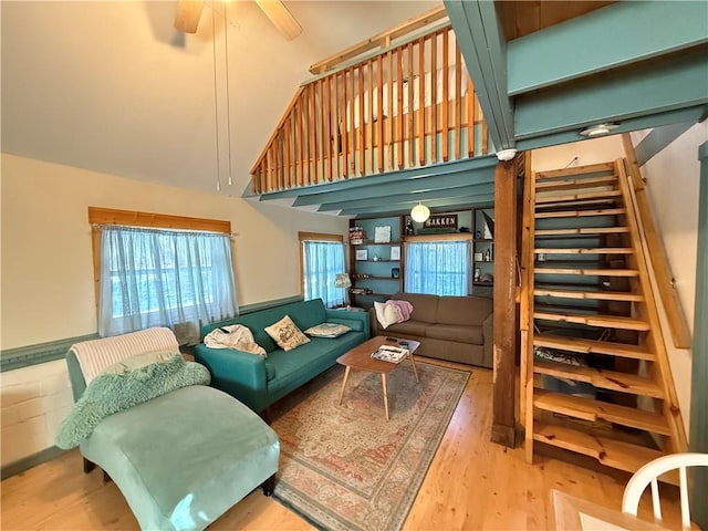 living room featuring ceiling fan, a high ceiling, and light wood-type flooring