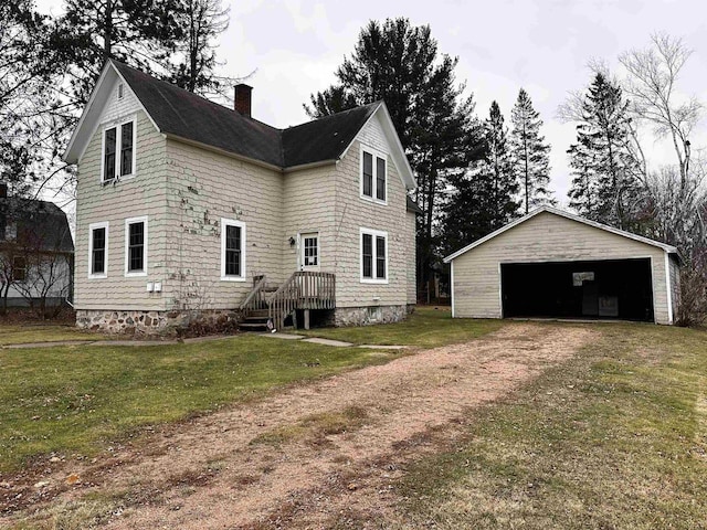 rear view of house with a garage, an outdoor structure, and a lawn