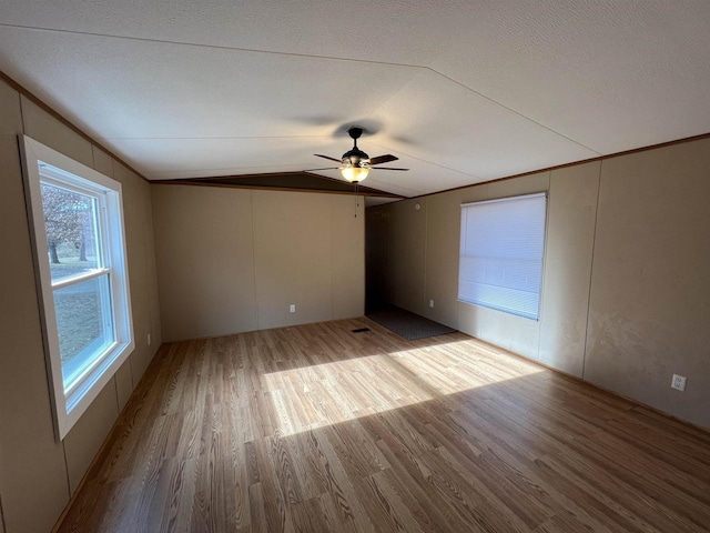 spare room with a textured ceiling, light hardwood / wood-style floors, ceiling fan, and lofted ceiling