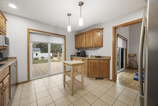 kitchen with stainless steel appliances, decorative light fixtures, and light hardwood / wood-style floors