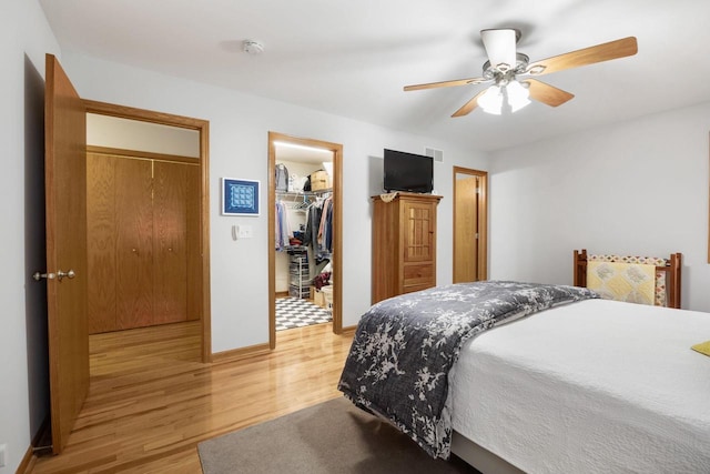 bedroom with ceiling fan, light hardwood / wood-style flooring, and a spacious closet