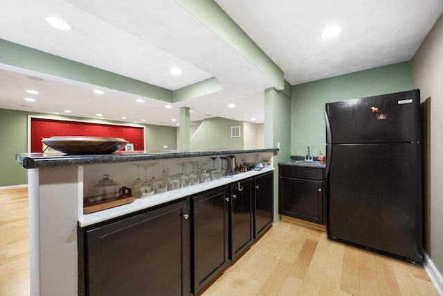 kitchen featuring black refrigerator, sink, light wood-type flooring, and kitchen peninsula