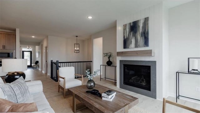 living room with a fireplace, an inviting chandelier, and light hardwood / wood-style flooring