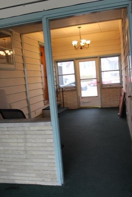 doorway to outside with wooden walls and a chandelier