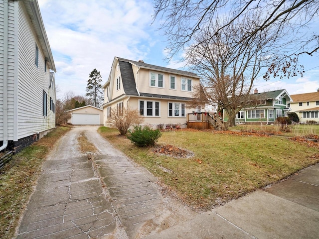 view of front of property with a garage, an outbuilding, and a front lawn