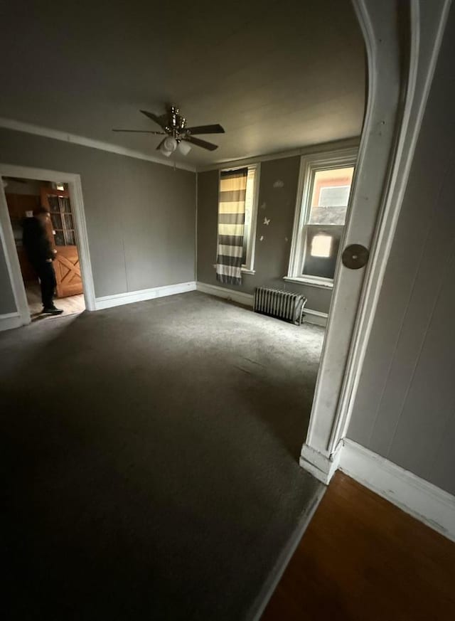 unfurnished room with ceiling fan, baseboards, and radiator