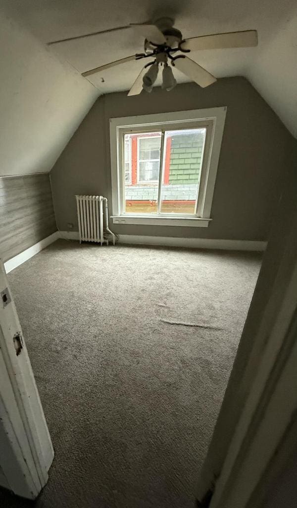 additional living space with vaulted ceiling, carpet flooring, a ceiling fan, and radiator