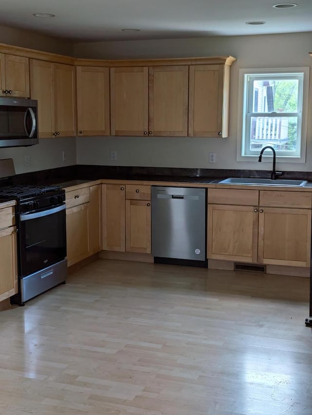 kitchen with light brown cabinetry, sink, light hardwood / wood-style flooring, and appliances with stainless steel finishes