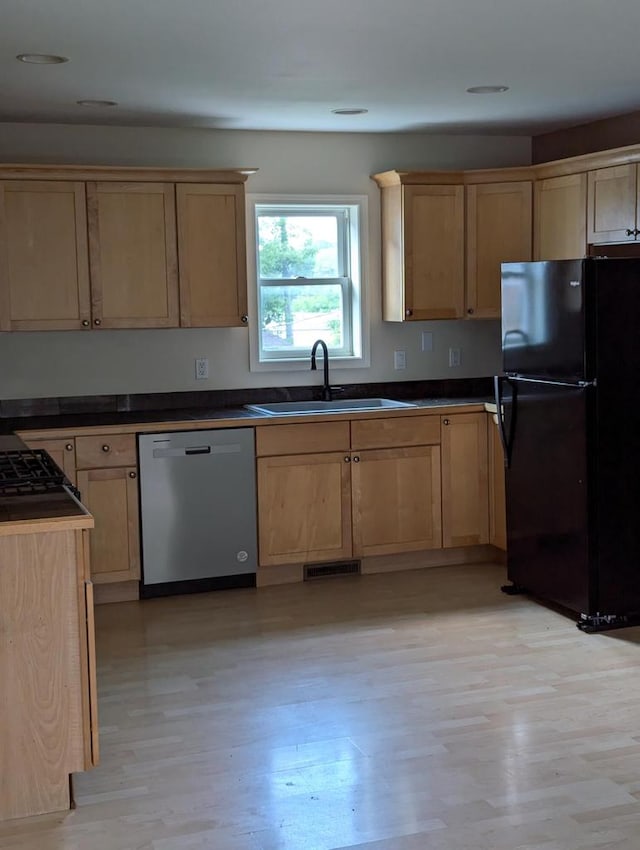 kitchen featuring stainless steel dishwasher, black refrigerator, light hardwood / wood-style floors, and sink