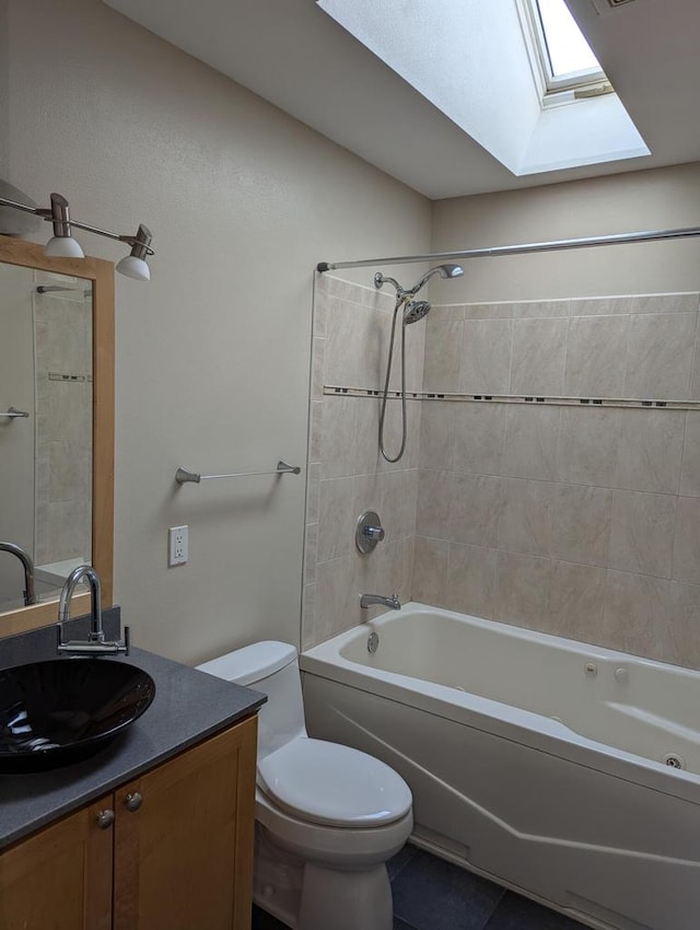 full bathroom with a skylight, tile patterned floors, toilet, vanity, and tiled shower / bath