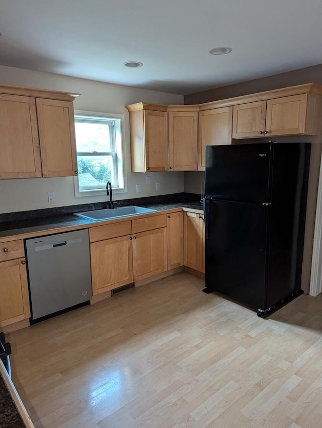 kitchen with dishwasher, black fridge, sink, and light hardwood / wood-style flooring