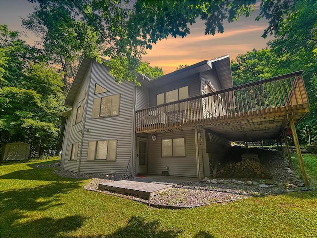 back house at dusk featuring a lawn, a patio area, and a wooden deck