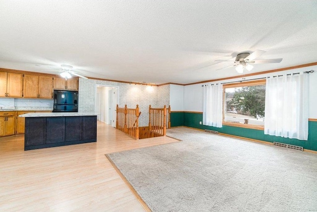 interior space with a textured ceiling, ceiling fan, crown molding, and light hardwood / wood-style flooring