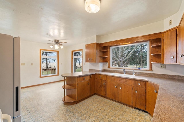 kitchen featuring kitchen peninsula, ceiling fan, and sink