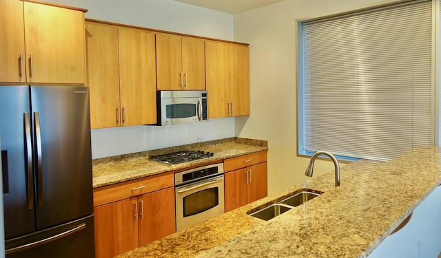 kitchen with light stone counters, sink, kitchen peninsula, and stainless steel appliances